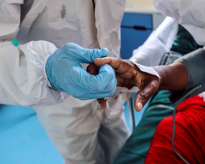 Doctors gather around a critically ill patient. The faces of patients are not shown to prevent stigmatisation and medical staff cannot be named