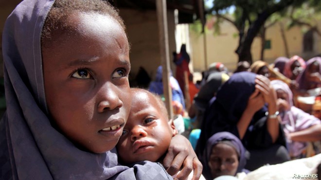 An internally displaced Somali girl carries her sibling as they wait to collect food relief from the World Food Program (WFP) at a settlement in the capital, Mogadishu, in 2011.