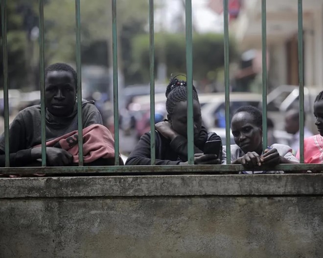 People stand outside a polling station in Eldoret, Kenya, Wednesday Aug. 10, 2022. Kenyans are waiting for results in the presidential elections that saw opposition leader Raila Odinga facing Deputy President William Rutoto in their bid to succeed President Uhuru Kenyatta who stayed in power for a decade.  BRIAN INGANGA / AP PHOTO